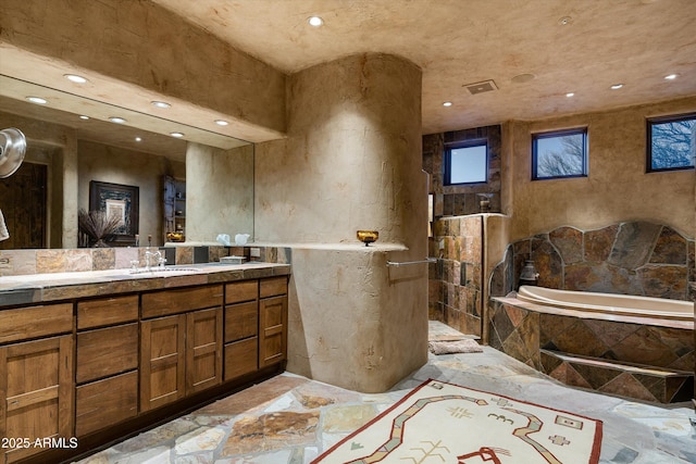 bathroom with vanity and a relaxing tiled tub