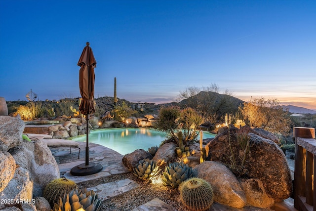 pool at dusk with a mountain view and a patio