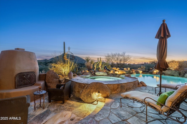 patio terrace at dusk featuring a pool with hot tub