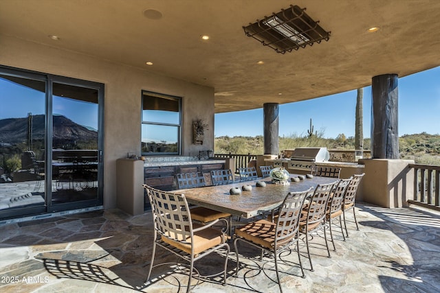 view of patio with exterior kitchen, a mountain view, and a grill