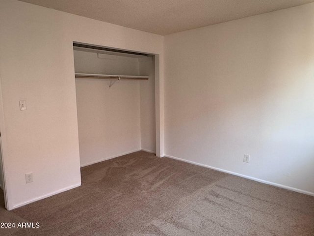 unfurnished bedroom with carpet, a closet, and baseboards