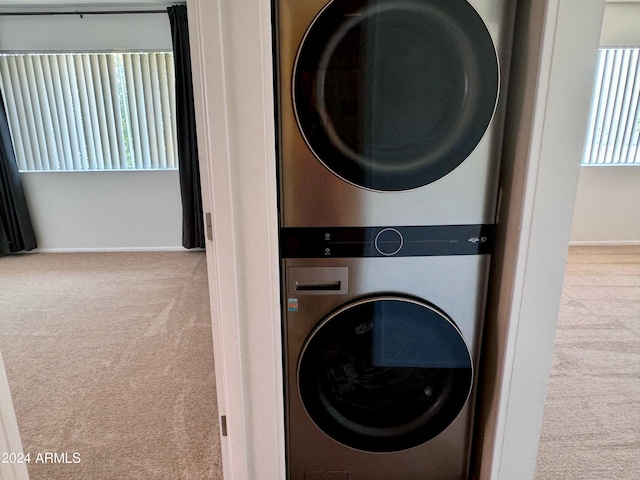 clothes washing area featuring carpet flooring, estacked washer and dryer, and baseboards