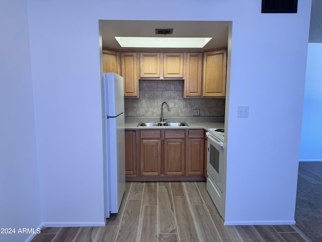 kitchen featuring white appliances, a sink, wood tiled floors, light countertops, and decorative backsplash