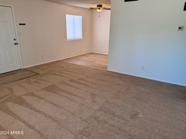 empty room with carpet, a ceiling fan, baseboards, and a textured ceiling