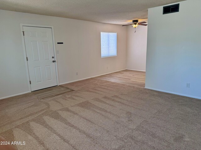 carpeted spare room with a ceiling fan, a textured ceiling, and baseboards