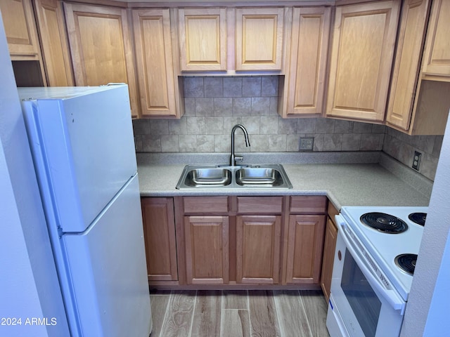 kitchen with white appliances, a sink, light countertops, and light wood-style floors