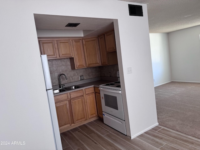 kitchen with a sink, white appliances, tasteful backsplash, dark wood-type flooring, and baseboards