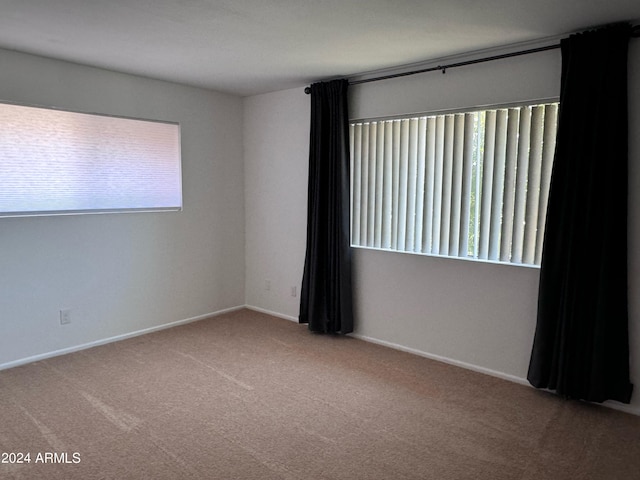 carpeted empty room with plenty of natural light and baseboards