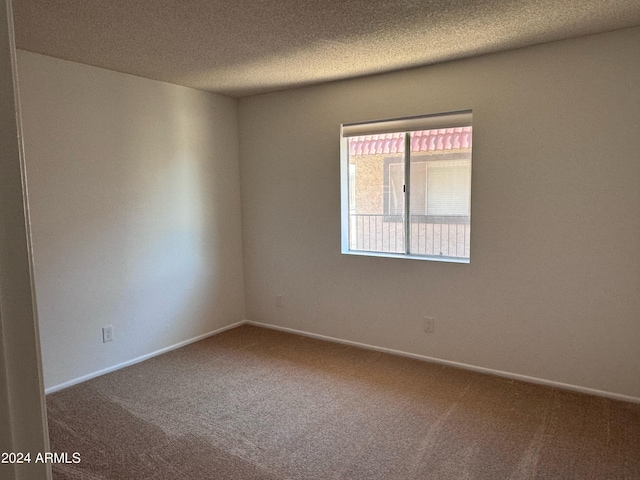 spare room featuring carpet, a textured ceiling, and baseboards