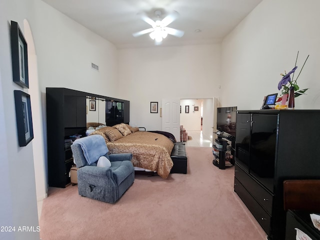 bedroom featuring ceiling fan, a towering ceiling, and carpet