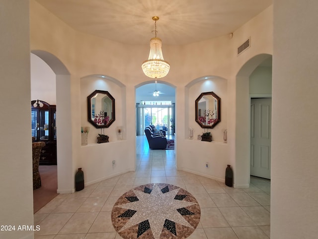 tiled foyer entrance featuring ceiling fan with notable chandelier