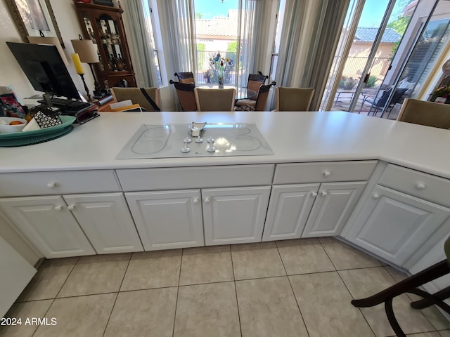 kitchen featuring white cabinets, electric cooktop, and light tile patterned flooring