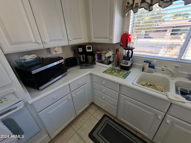 kitchen with white cabinets, light tile patterned floors, and sink