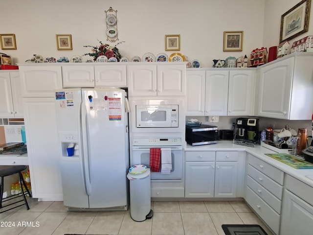 kitchen featuring white cabinetry, light tile patterned floors, and white appliances