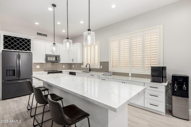 870 E Megan St, Gilbert, AZ 85295 - kitchen featuring appliances with stainless steel finishes, a sink, white cabinets, a breakfast bar, and tasteful backsplash