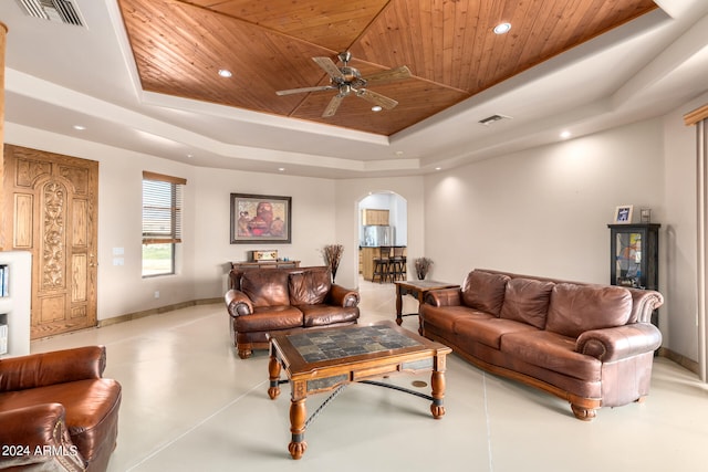 tiled living room featuring ceiling fan, wood ceiling, and a raised ceiling