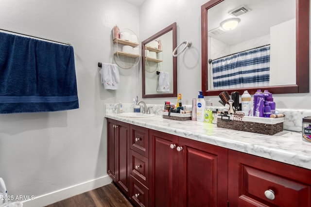 bathroom featuring visible vents, baseboards, a shower with curtain, wood finished floors, and vanity