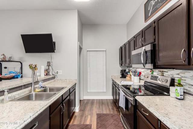 kitchen with a sink, dark wood finished floors, stainless steel appliances, dark brown cabinetry, and light countertops