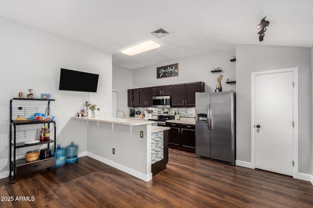 kitchen featuring tasteful backsplash, a peninsula, stainless steel appliances, and dark wood-style flooring