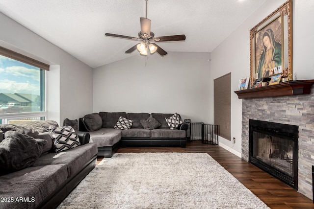 living room with a ceiling fan, a fireplace, dark wood-style flooring, vaulted ceiling, and a textured ceiling