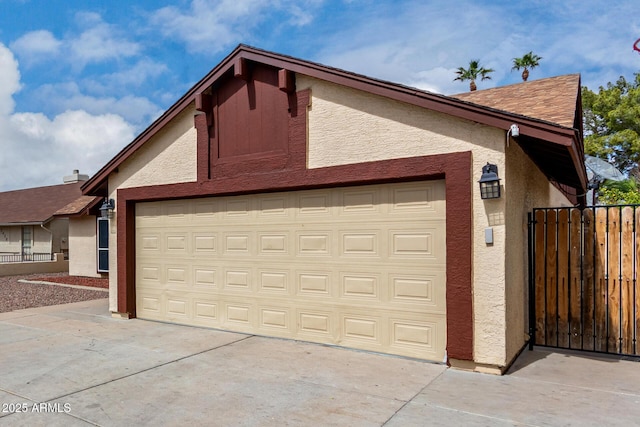 garage with concrete driveway and fence