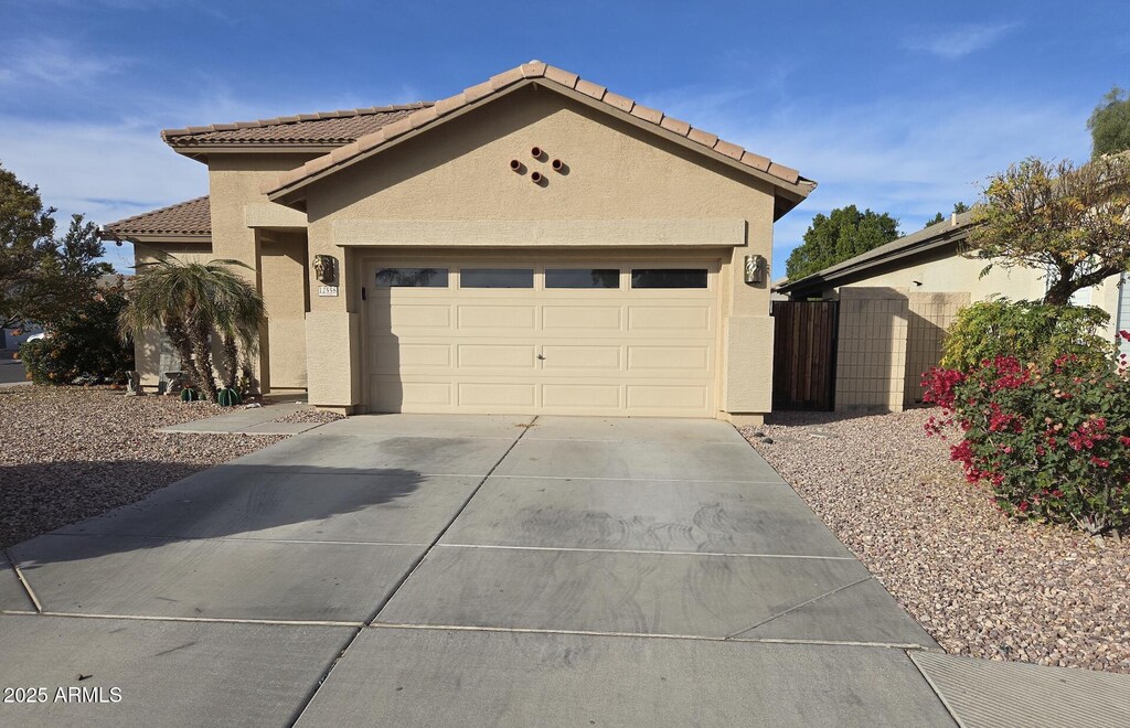 12558 W Jefferson St, Avondale, AZ 85323 - view of front of home with driveway, a tile roof, an attached garage, and stucco siding