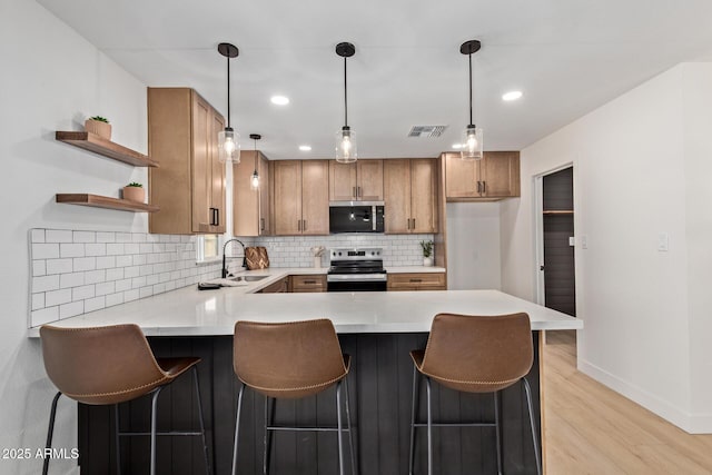 802 E Navajo Ave, Apache Junction, AZ 85119 - kitchen with stainless steel appliances, brown cabinetry, a peninsula, light wood finished floors, and backsplash