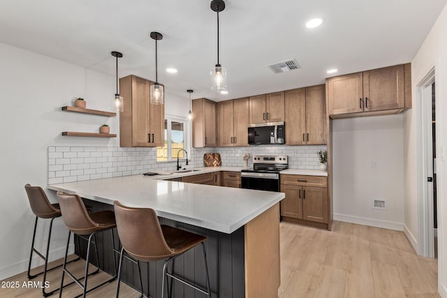 802 E Navajo Ave, Apache Junction, AZ 85119 - kitchen with stainless steel appliances, a peninsula, brown cabinets, light wood-type flooring, and backsplash