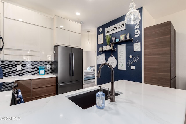 kitchen with freestanding refrigerator, a sink, decorative backsplash, white cabinets, and modern cabinets