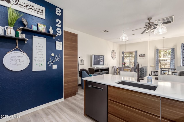 kitchen featuring visible vents, open floor plan, dishwasher, brown cabinetry, and a sink