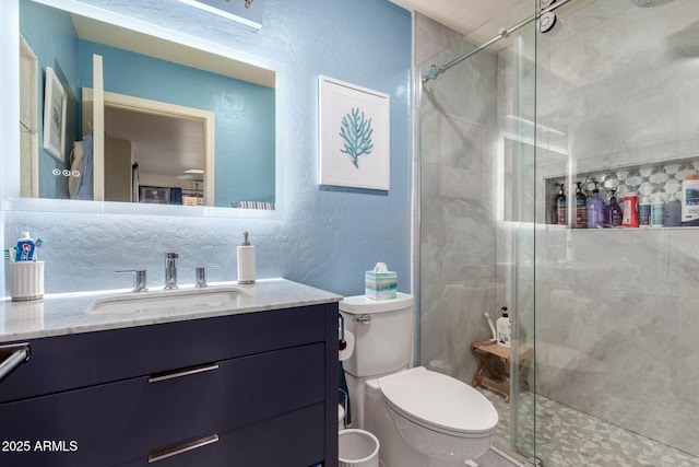 bathroom featuring a shower stall, toilet, vanity, and a textured wall