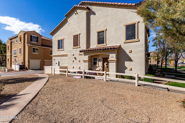 rear view of house featuring a tile roof, fence, and stucco siding