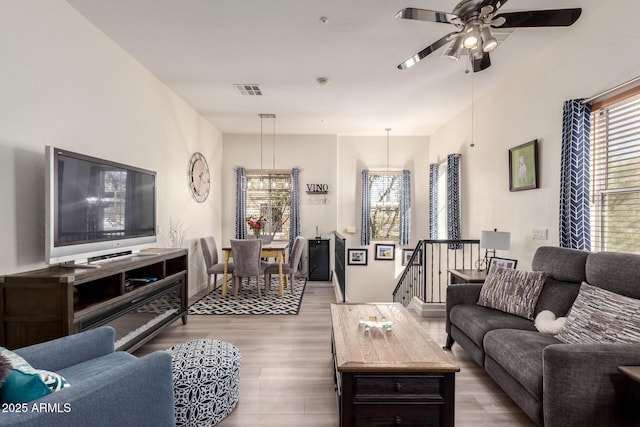 living room with wood finished floors, visible vents, and ceiling fan