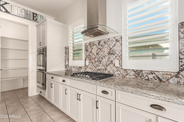 kitchen featuring light stone countertops, white cabinetry, island range hood, and stainless steel appliances