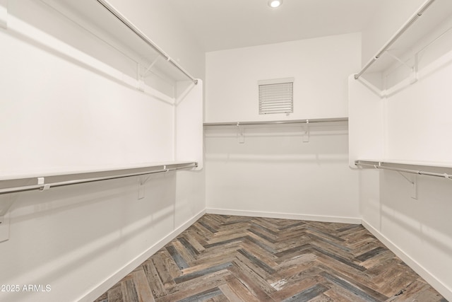 spacious closet with dark parquet flooring