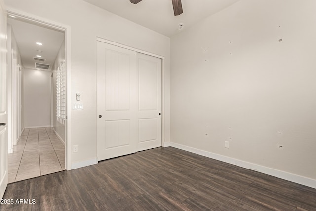 unfurnished bedroom featuring ceiling fan, a closet, and dark hardwood / wood-style flooring