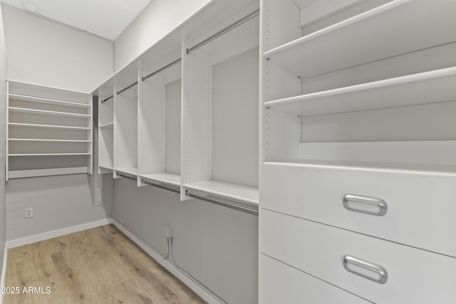 walk in closet with light hardwood / wood-style floors