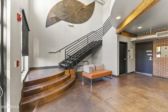 stairs with concrete flooring and brick wall