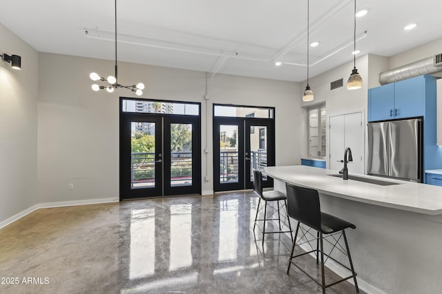 kitchen with french doors, a kitchen bar, blue cabinets, sink, and stainless steel fridge