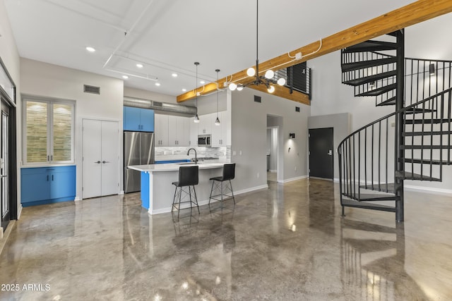 kitchen with a breakfast bar, appliances with stainless steel finishes, hanging light fixtures, a high ceiling, and white cabinets