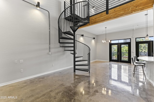 interior space featuring a towering ceiling, a notable chandelier, and french doors