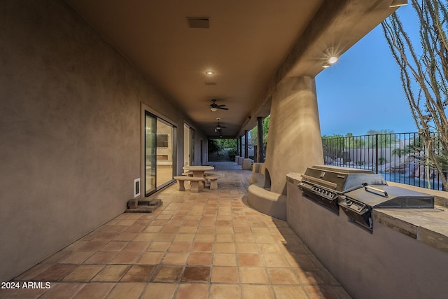 view of patio with ceiling fan, area for grilling, and exterior kitchen