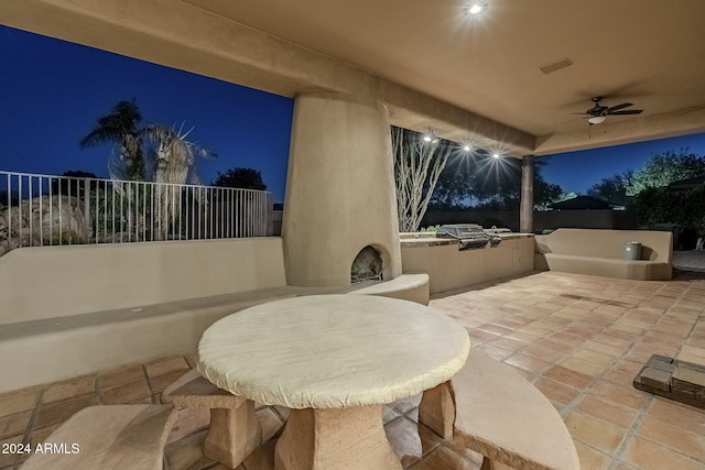 patio at twilight featuring an outdoor kitchen and ceiling fan