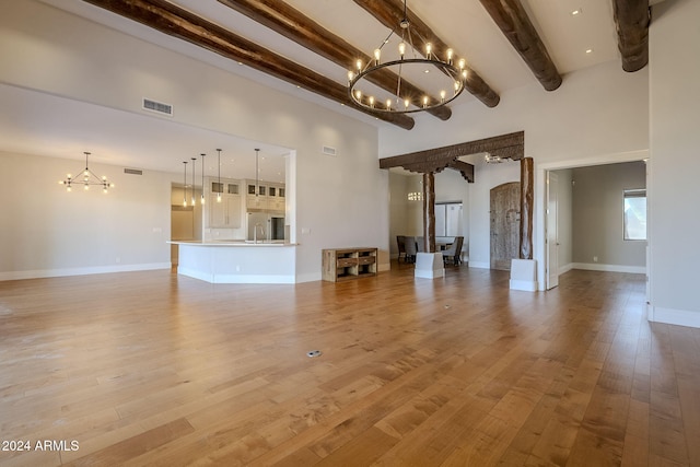 unfurnished living room featuring a high ceiling, beam ceiling, and light wood-type flooring