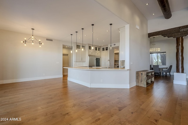 kitchen with sink, kitchen peninsula, hardwood / wood-style floors, white cabinets, and pendant lighting