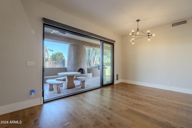 doorway to outside featuring wood-type flooring and an inviting chandelier