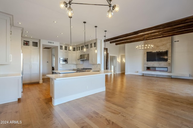 kitchen with white cabinets, kitchen peninsula, light hardwood / wood-style flooring, hanging light fixtures, and appliances with stainless steel finishes