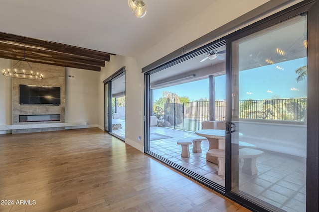 doorway to outside featuring hardwood / wood-style floors, a large fireplace, and ceiling fan with notable chandelier