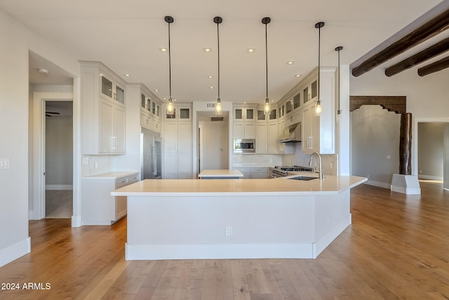 kitchen with light hardwood / wood-style floors, built in appliances, beam ceiling, hanging light fixtures, and white cabinets