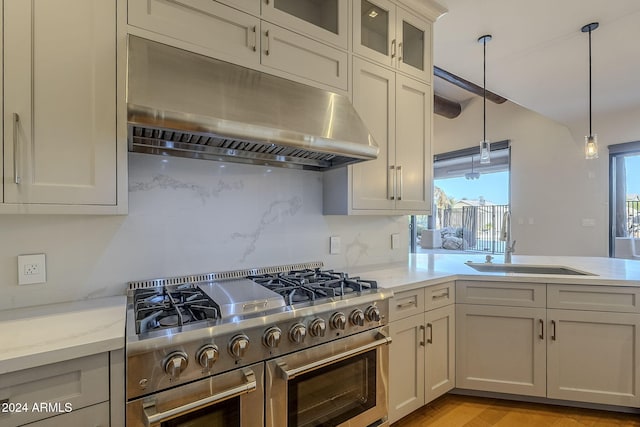 kitchen with high end range, a healthy amount of sunlight, sink, and decorative light fixtures